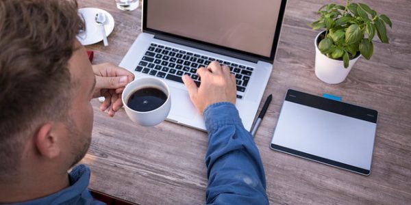 person mit kaffe am laptop